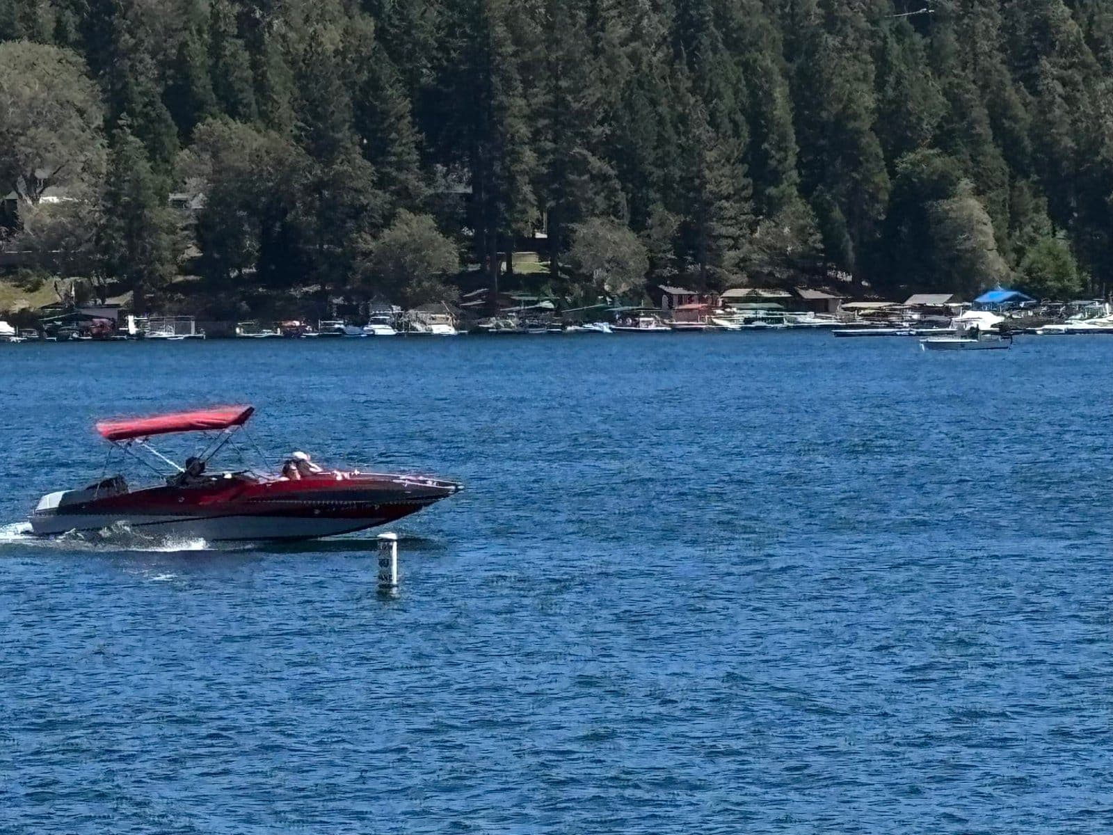 A red motorboat crossing the open water at Lake Arrowhead