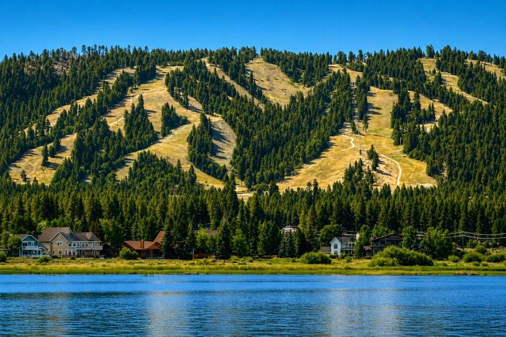 Big Bear Lake in the foreground, shoreline homes among pines, and ski runs on the forested hillside.