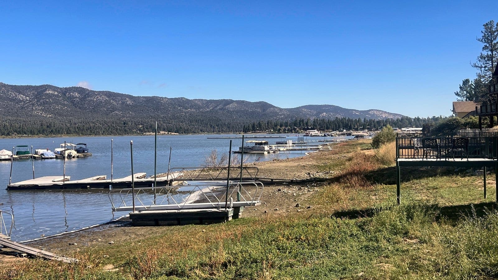 Boat docks along a grassy lake shoreline with mountains on the horizon in the San Bernardino Mountains